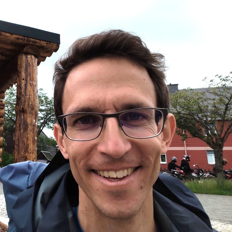 Gesicht eines jungen Mannes mit Brille und Regenjacke im Freien